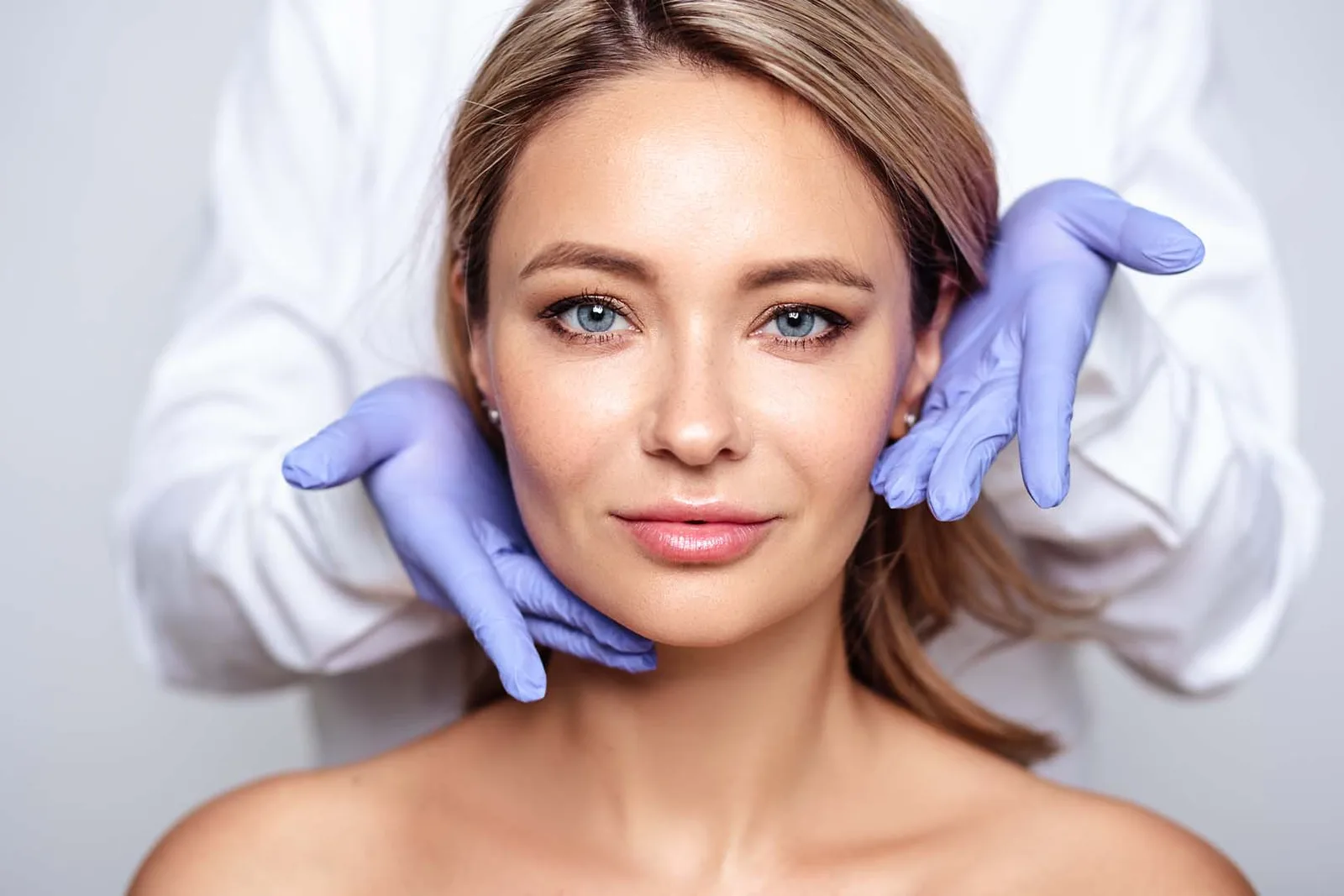 A dentist assessing a patient’s facial structure before injectable treatment
