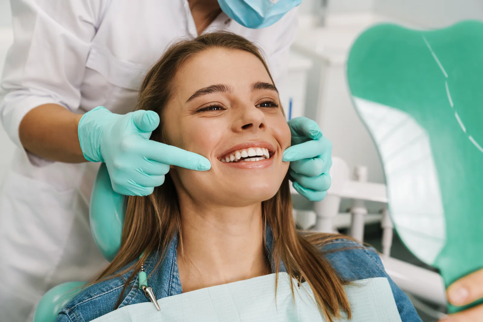 A patient admiring her completed smile makeover in a hand mirror